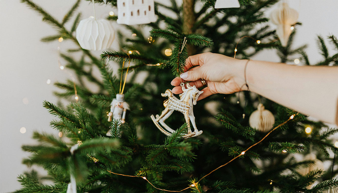Weihnachtsbaumdekoration mit Holzfiguren und Lichtern, inspiriert von den Weihnachtsdeko-Trends 2024, für eine festliche und gemütliche Atmosphäre zu den Feiertagen.