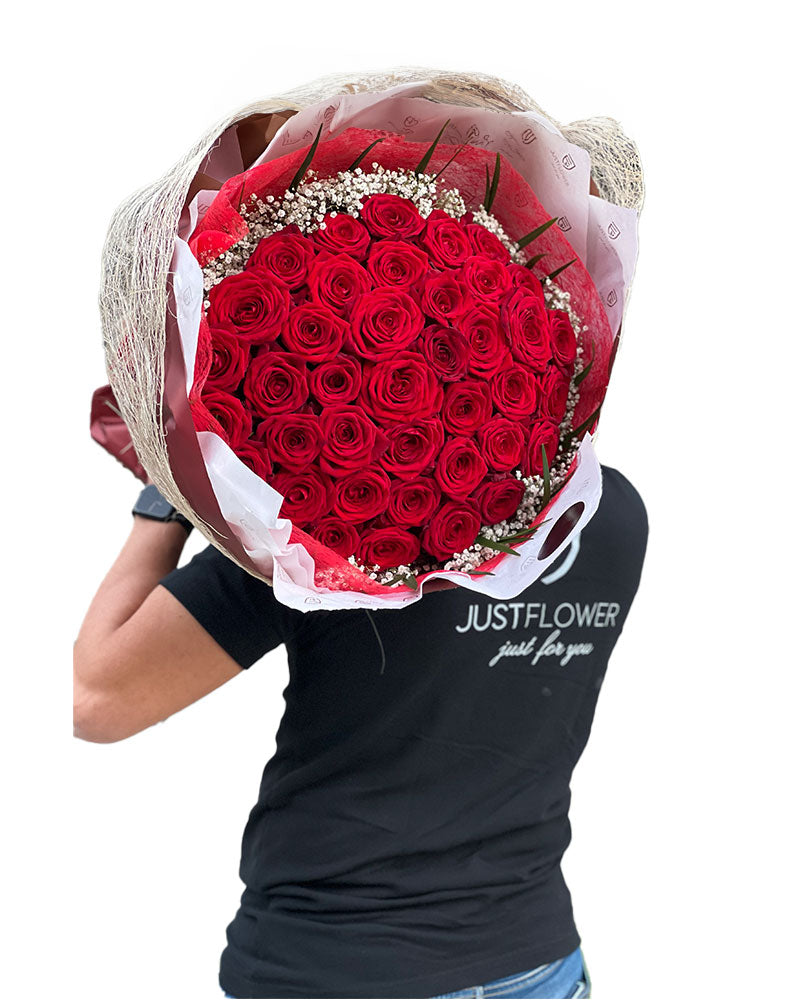 Roter Rosenstrauß mit 50 frischen Rosen – präsentiert von einem Mitarbeiter von JustFlower.ch, einem führenden Anbieter von exklusiven Blumenarrangements.