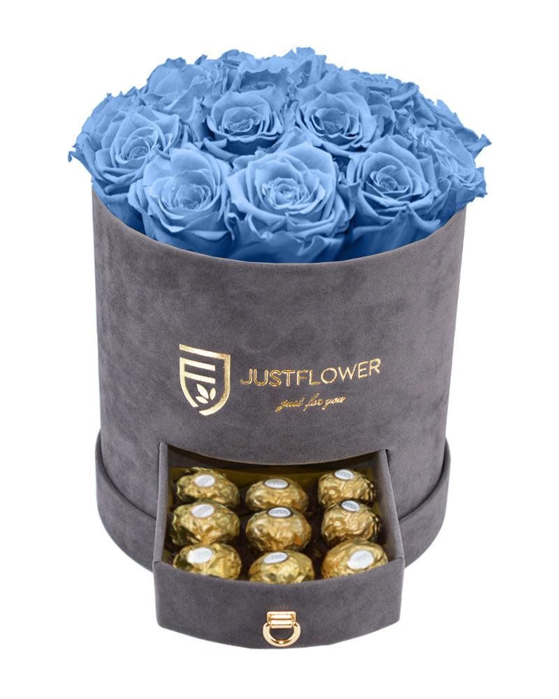 Rosenbox mit blauen Infinity Rosen – Graue Rosenbox mit konservierten hellblauen ewigen Rosen und einer Schublade voller Ferrero Rocher. Bestellen Sie diese edle Rosenbox bei JustFlower.ch für das perfekte Geschenk.